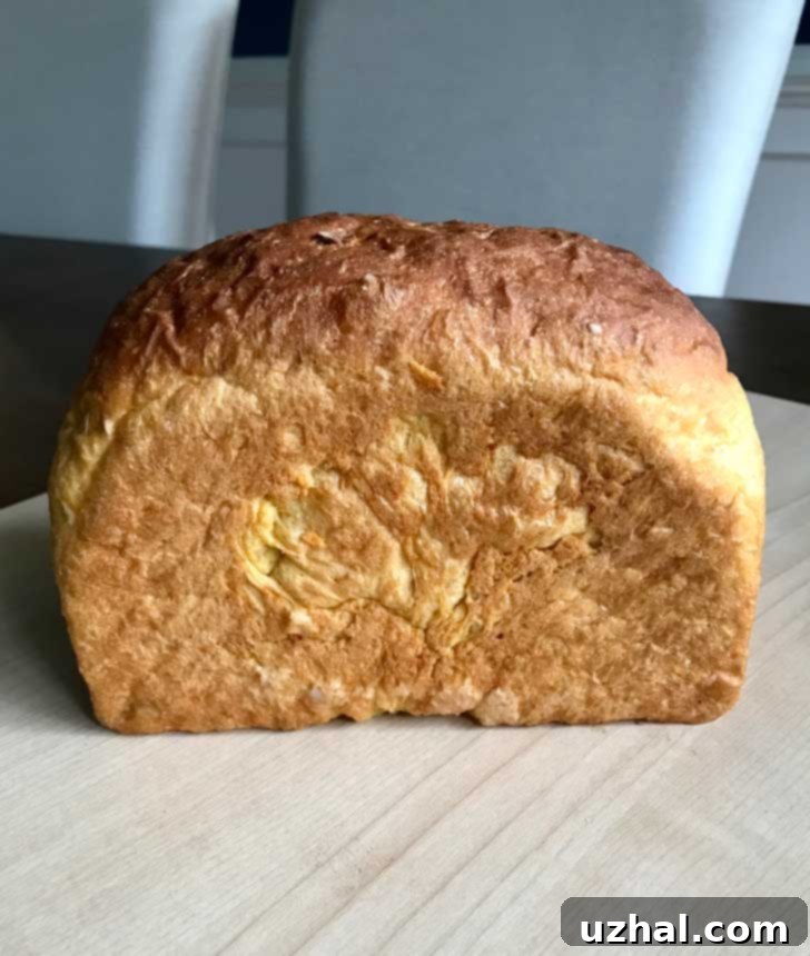 Freshly baked sweet potato yeast bread resting on a wooden cutting board, ready for slicing.
