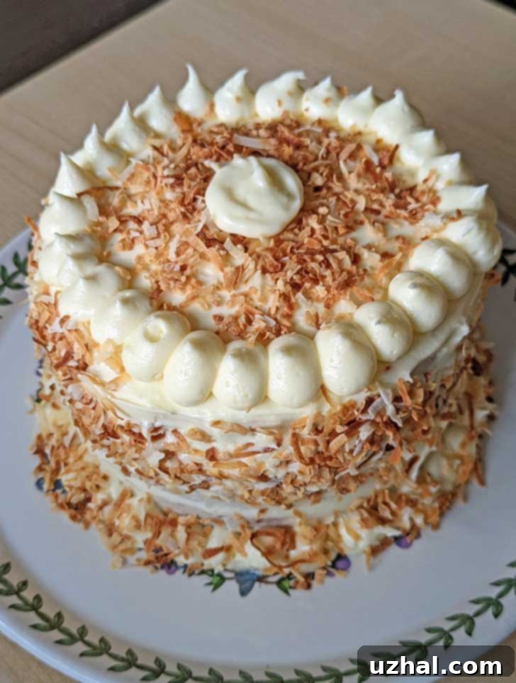 6-Inch Coconut Layer Cake 2 A beautifully frosted 6-inch coconut cake with cream cheese icing and lots of toasted coconut on a white plate.