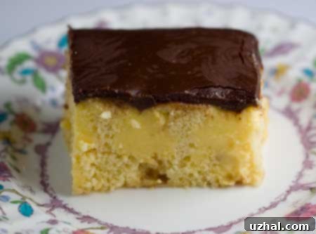 Homemade Boston Cream Poke Cake baked in an 8-inch pan, featuring a yellow cake base, creamy filling, and chocolate topping.