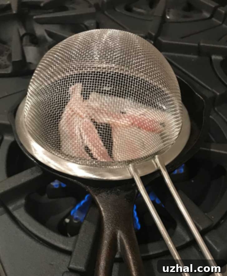 A small cast iron skillet with a makeshift splatter shield, ready for baking half a batch of cornbread.