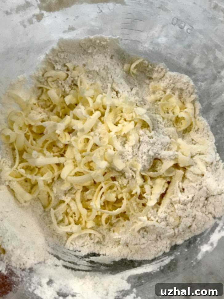 Close-up of cold butter grated directly into a flour mixture for scone dough.
