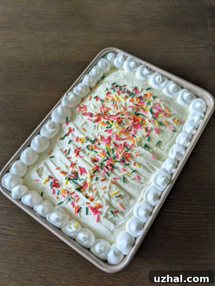 Close-up of a slice of Neapolitan Poke Cake, showing the distinct pink strawberry gelatin layer and creamy white frosting.