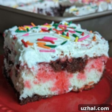 A vibrant slice of Neapolitan Poke Cake with distinct layers of cake, pink gelatin, and white frosting.