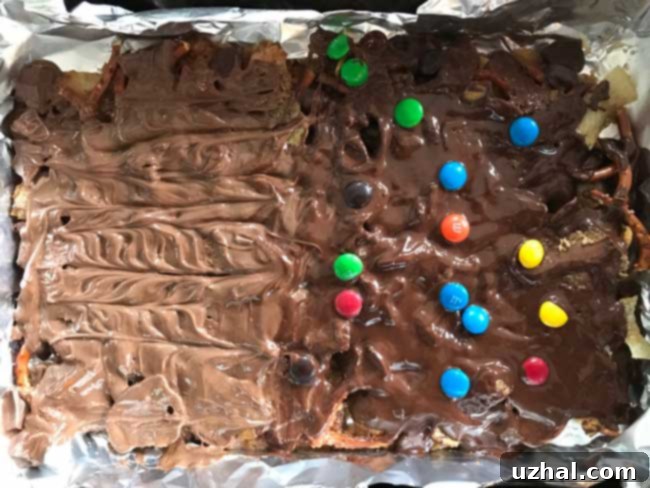 Freshly made Frito Candy in a baking pan, topped with melting chocolate and peanut butter cups.