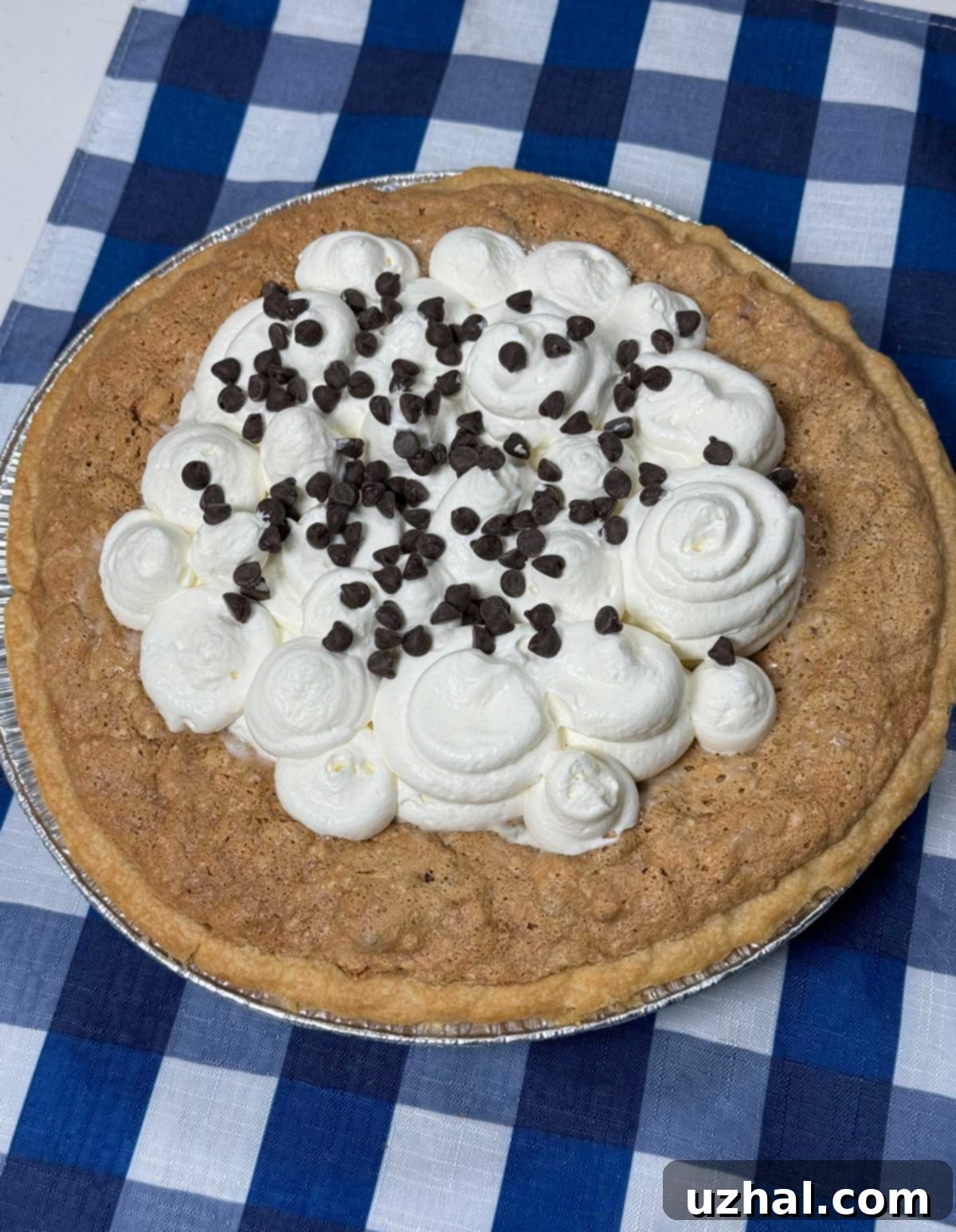 Close-up of a perfectly cut slice of Layered Chocolate Pecan Pie with a generous dollop of whipped cream on top, ready to be enjoyed.