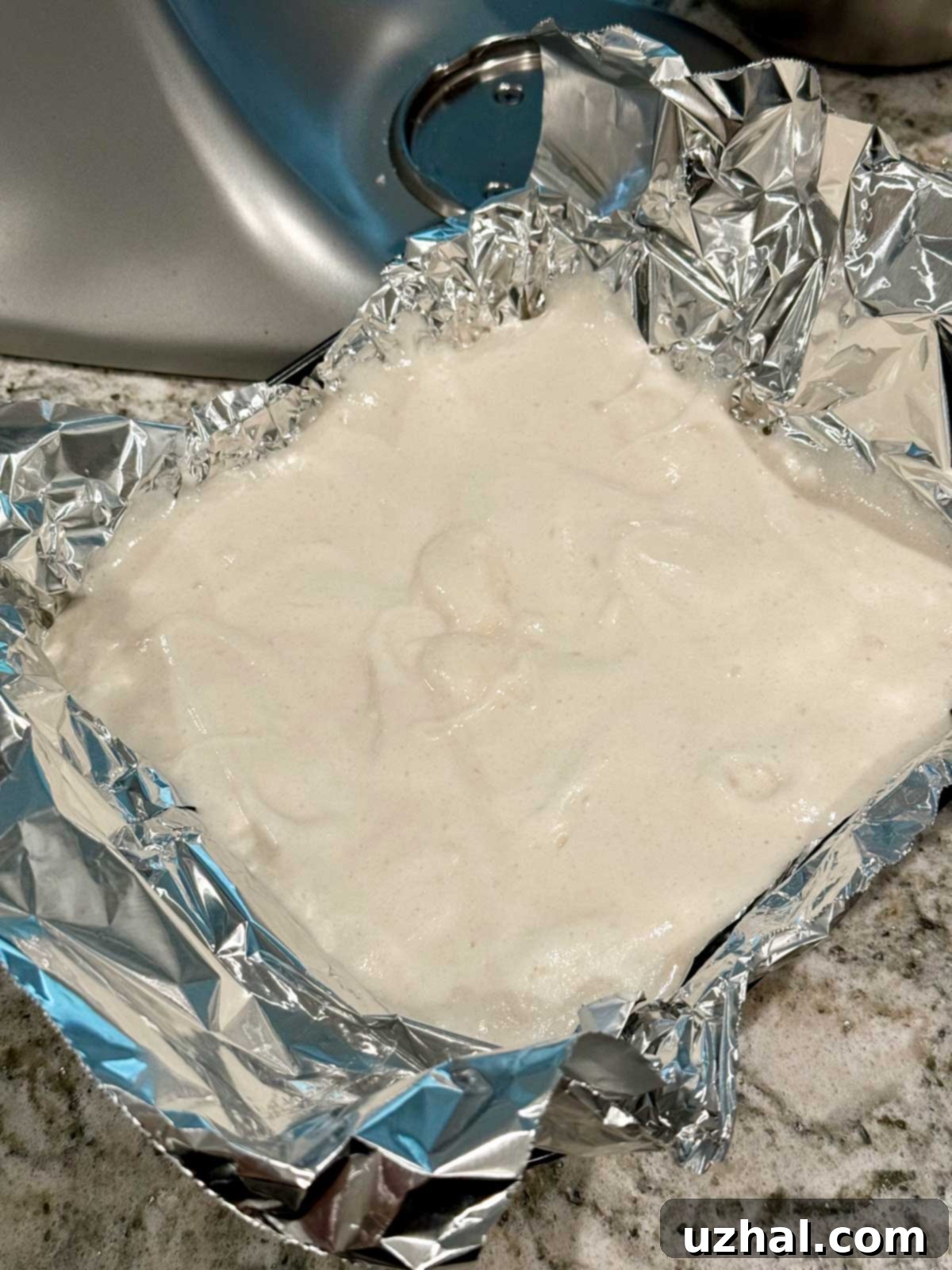 Angel food cake batter in a foil-lined square pan