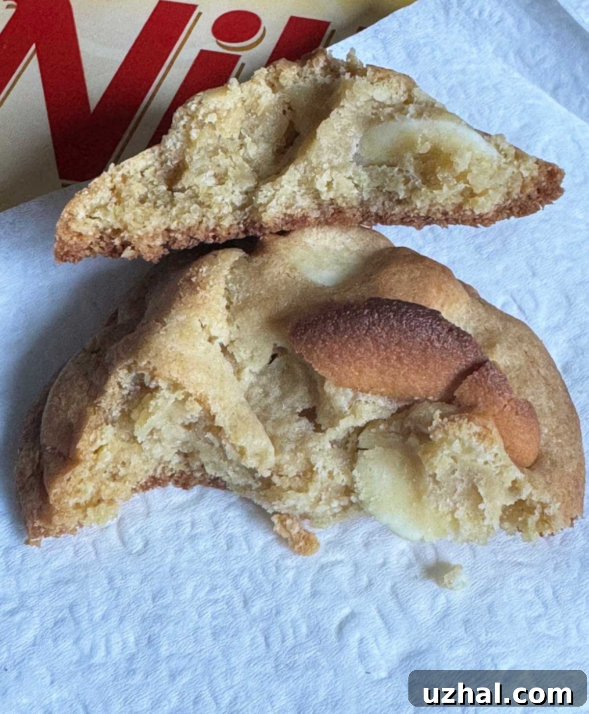 Broken jumbo banana pudding cookie showing its soft, chewy interior with Nilla Wafers and white chocolate chunks