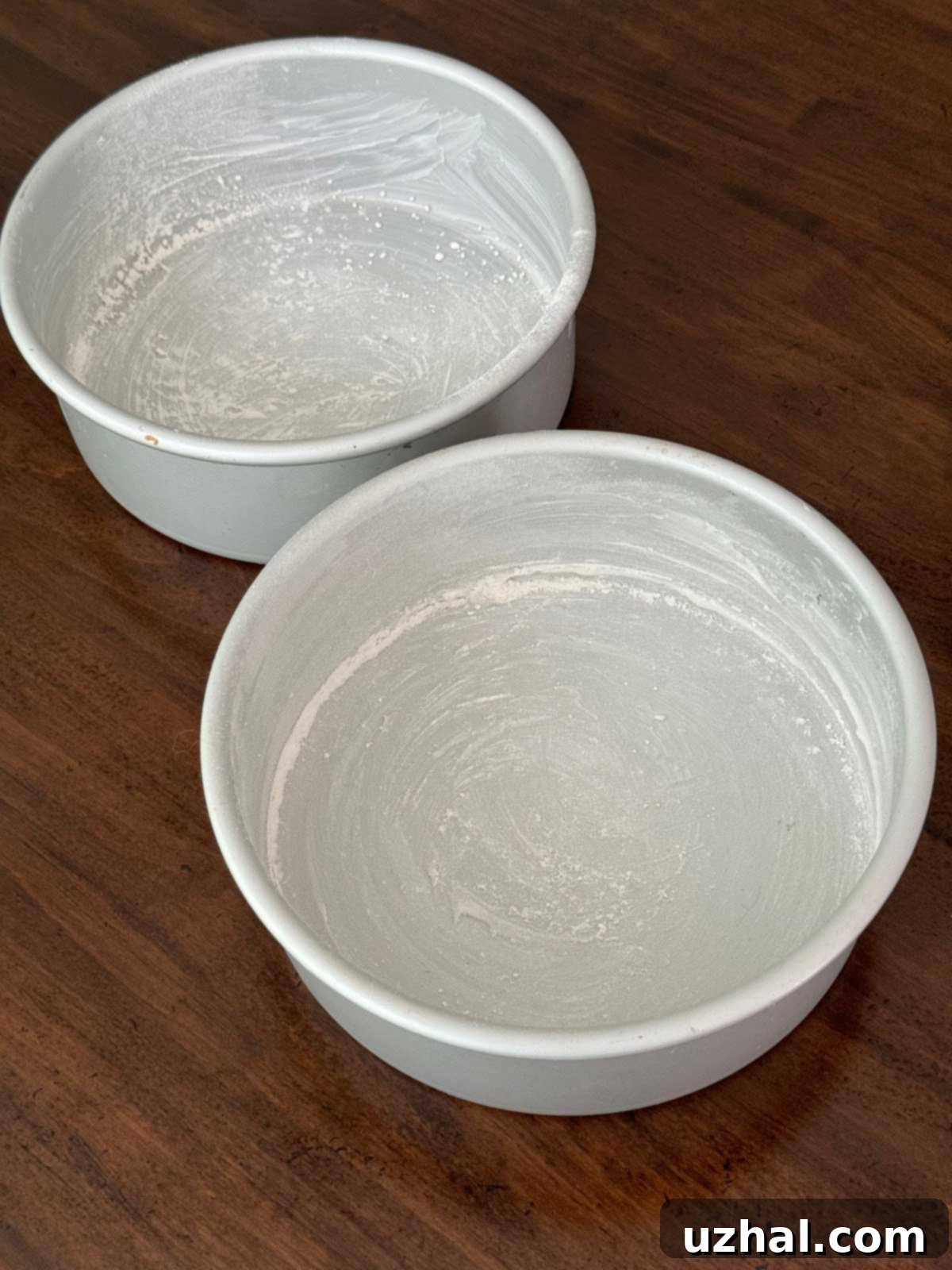 Grease and flour 2 8-inch cake pans meticulously before adding batter.