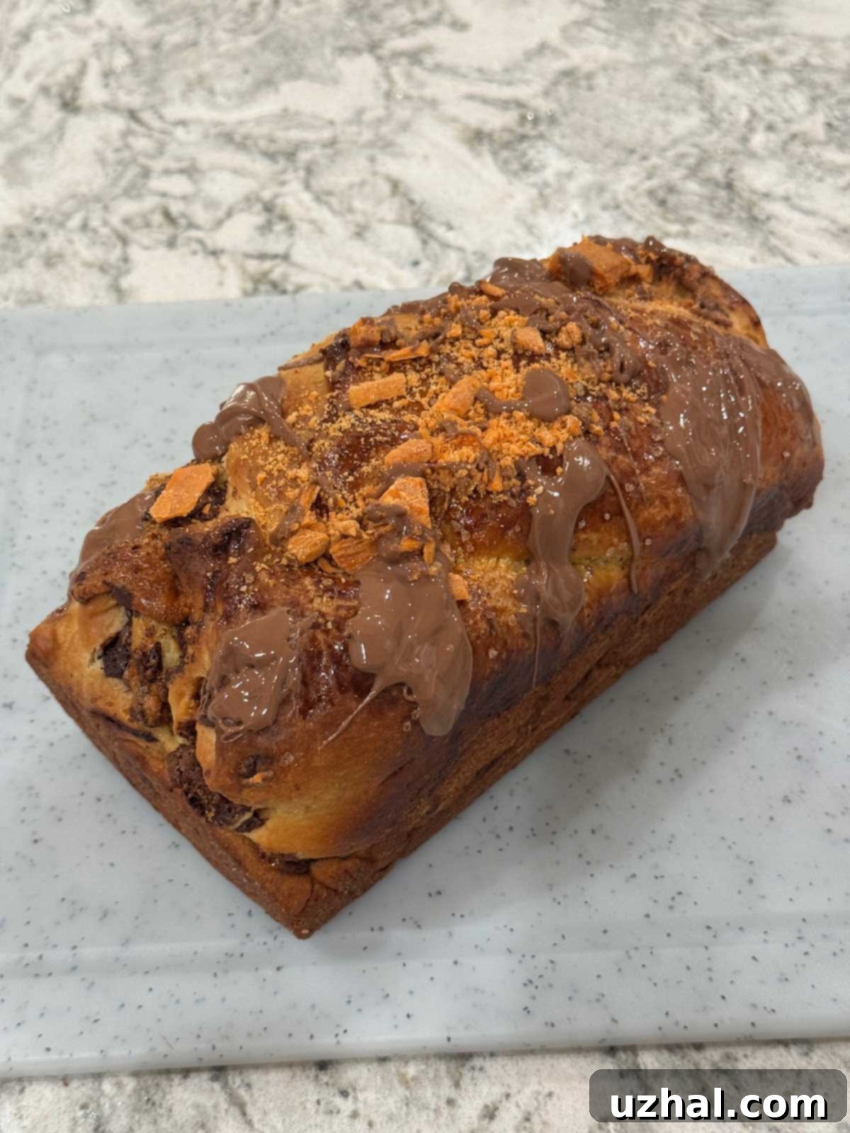 Close-up of a homemade Butterfinger Babka loaf, showcasing its unique topping and swirl.