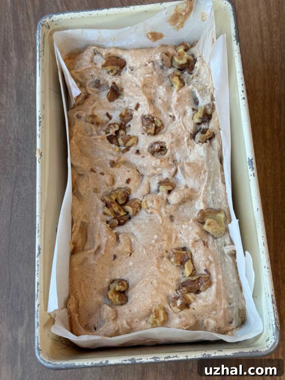 Baked biscotti loaf cooling in a parchment-lined loaf pan before slicing