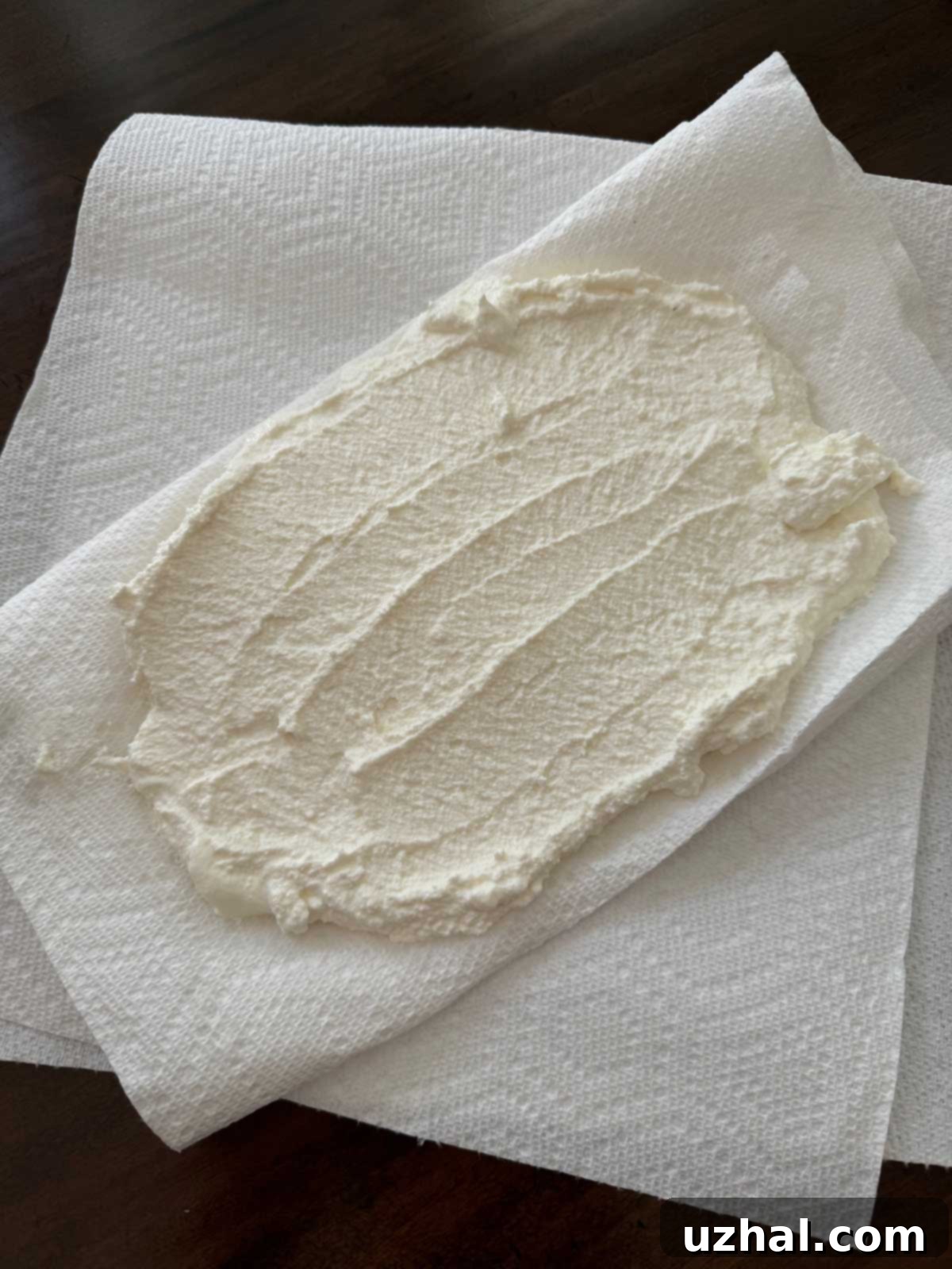 Ricotta cheese being drained on a stack of paper towels, a crucial step for achieving a perfectly creamy and set Ricotta Sour Cream Pie filling.