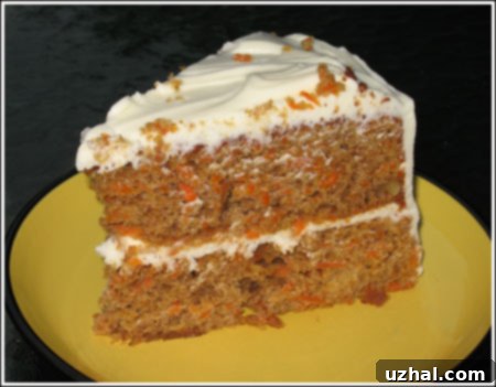 A beautifully frosted slice of homemade carrot cake with cream cheese frosting, garnished with nuts.