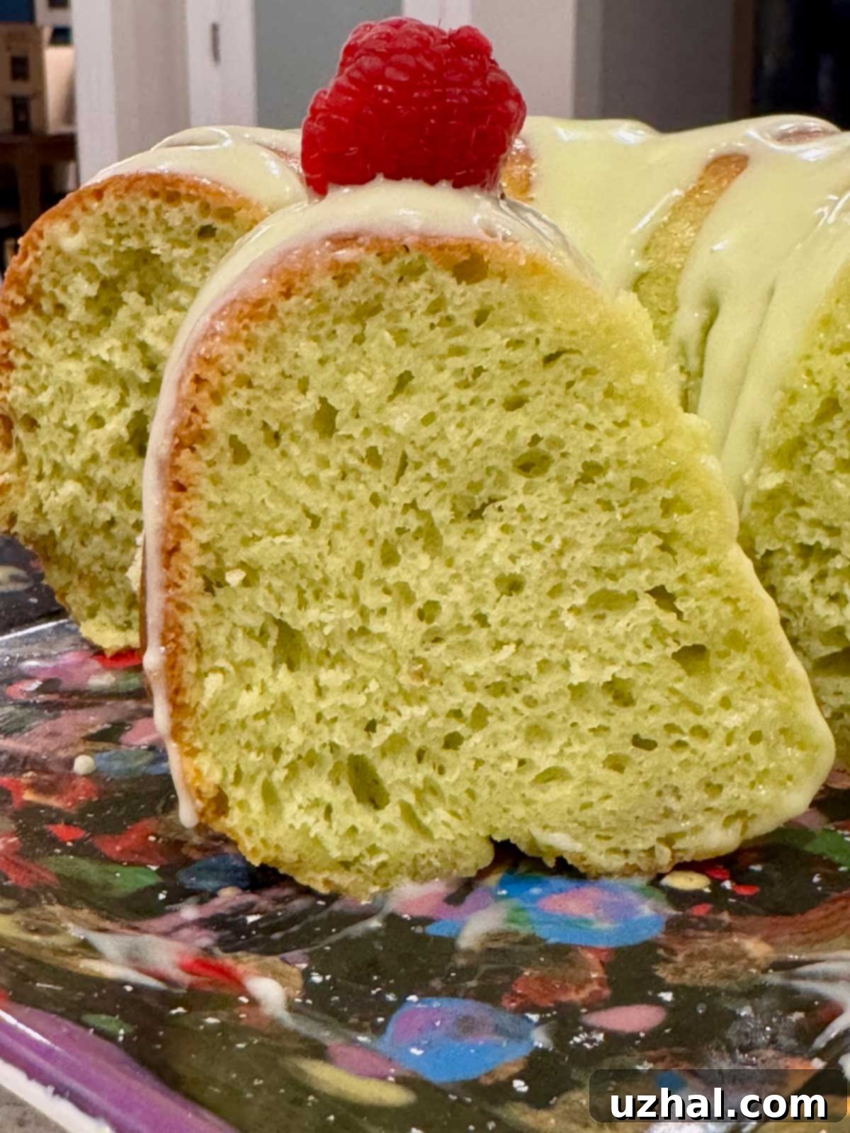 Midori Melon Bundt 3 Close-up texture of a moist, doctored cake mix Bundt cake with Midori liqueur and creamy cream cheese icing, garnished with a few berries.