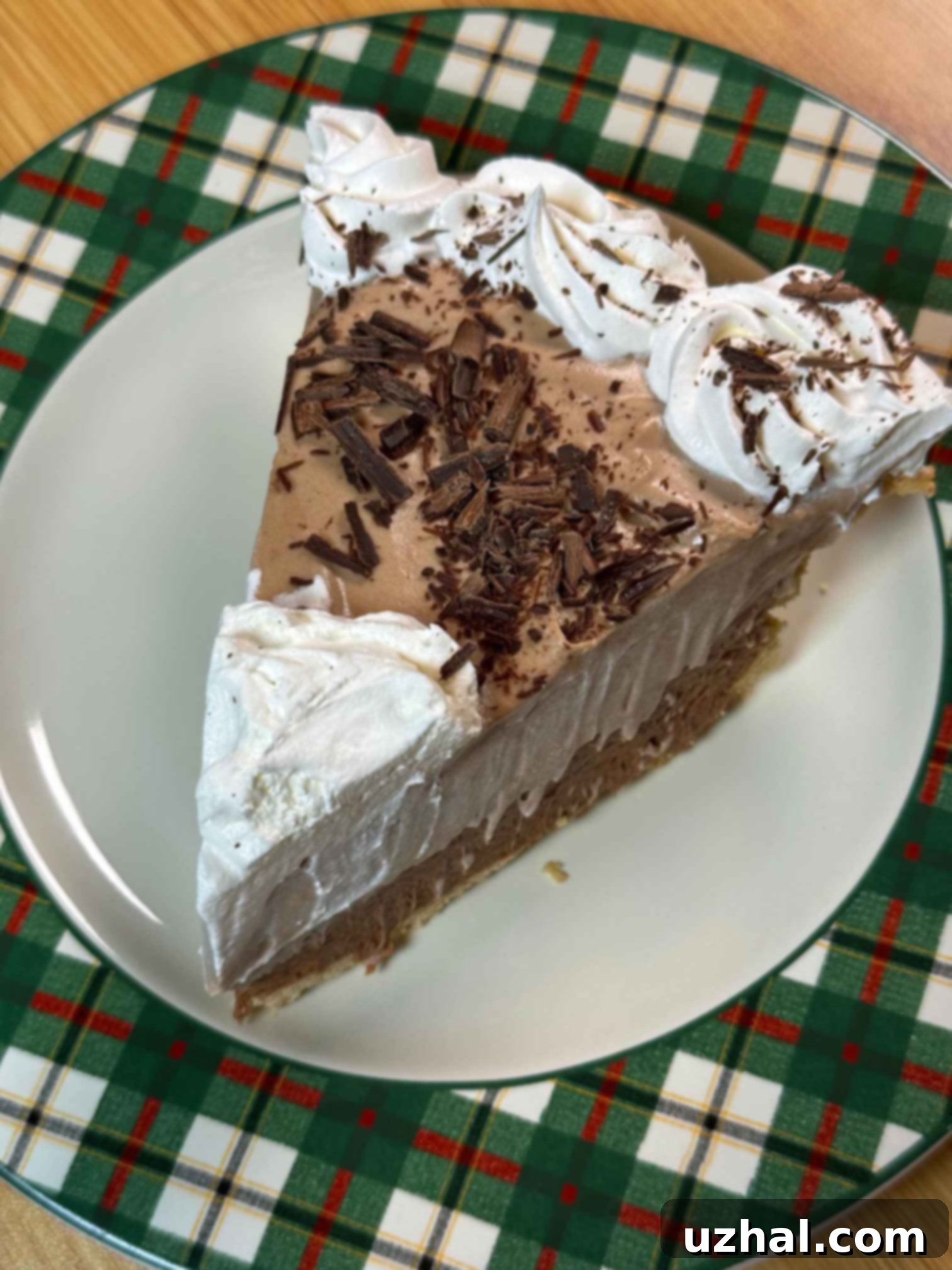 A beautifully presented slice of layered chocolate pie, showcasing two distinct layers of rich, chocolate-flavored whipped cream filling, artfully placed in a golden-brown crust.
