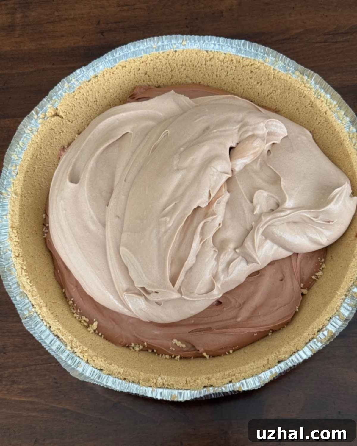 An overhead view of the layered chocolate cream pie, clearly displaying the convenience of a store-bought graham cracker crust and the distinct bittersweet and milk chocolate layers before chilling.