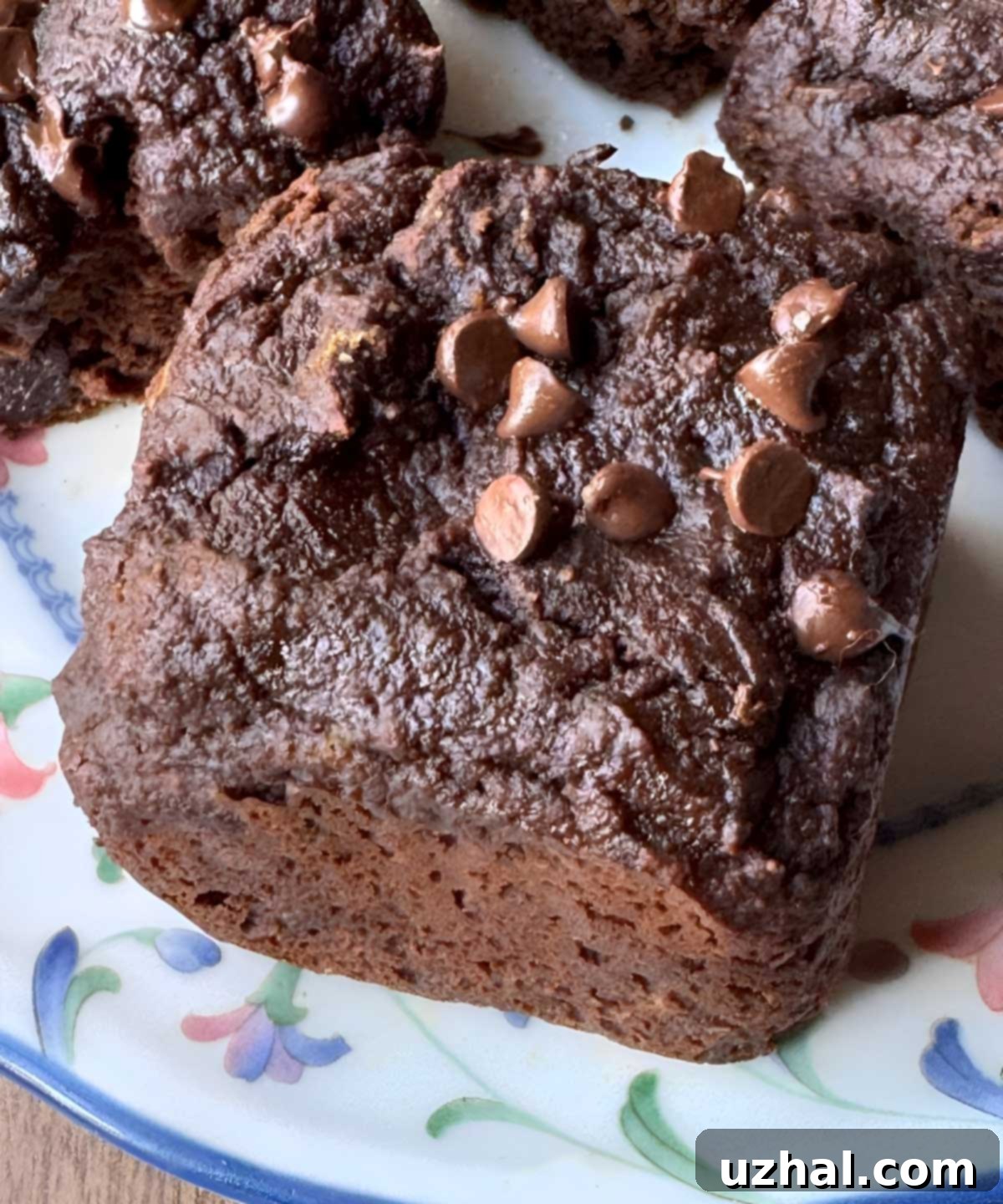 Oat Fiber Brownies that are square shaped individual servings sitting on a flowered plate, ready to be enjoyed.