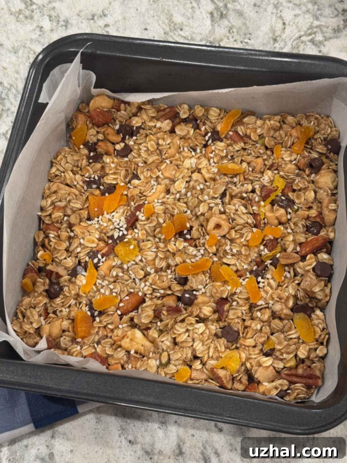 Soom Tahini Granola Bars 3 Unbaked Tahini Granola Bars mixture pressed evenly into a parchment-lined 8-inch square pan, ready for baking.