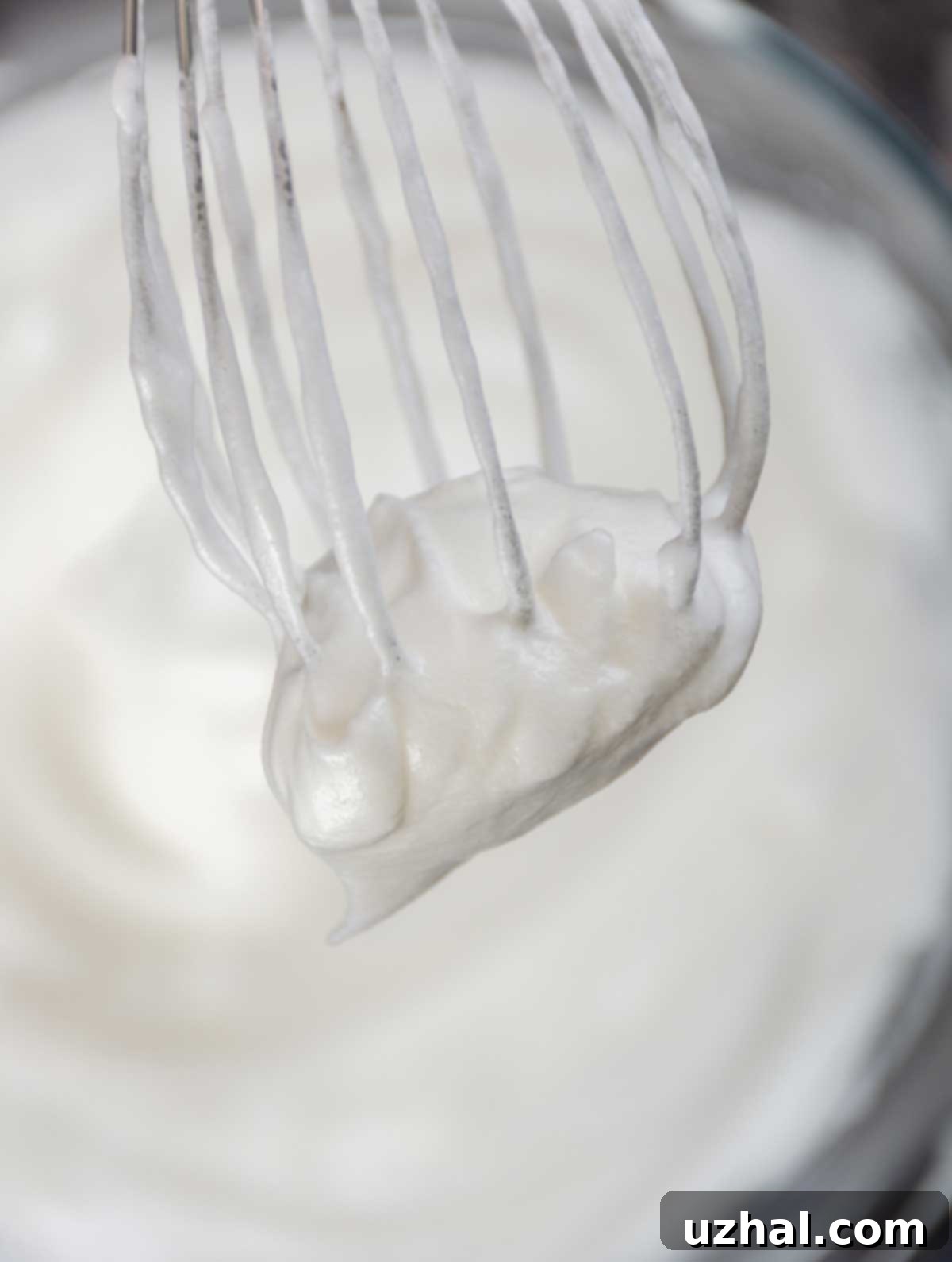 Close-up of fluffy egg whites whipped to soft peaks, ready to be folded into waffle batter.