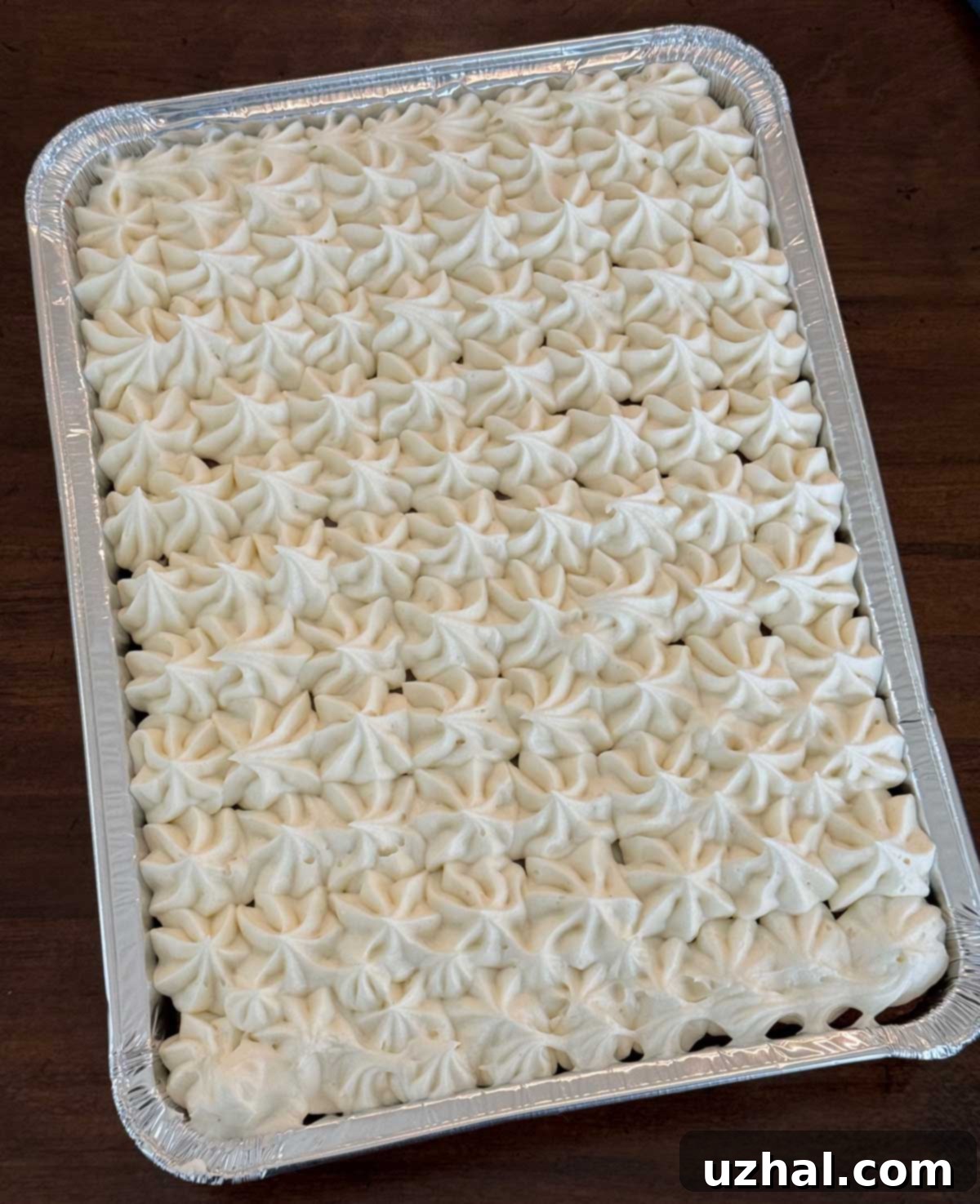 Classic carrot cake with whipped cream cheese frosting baked in a disposable 9x13 inch pan.