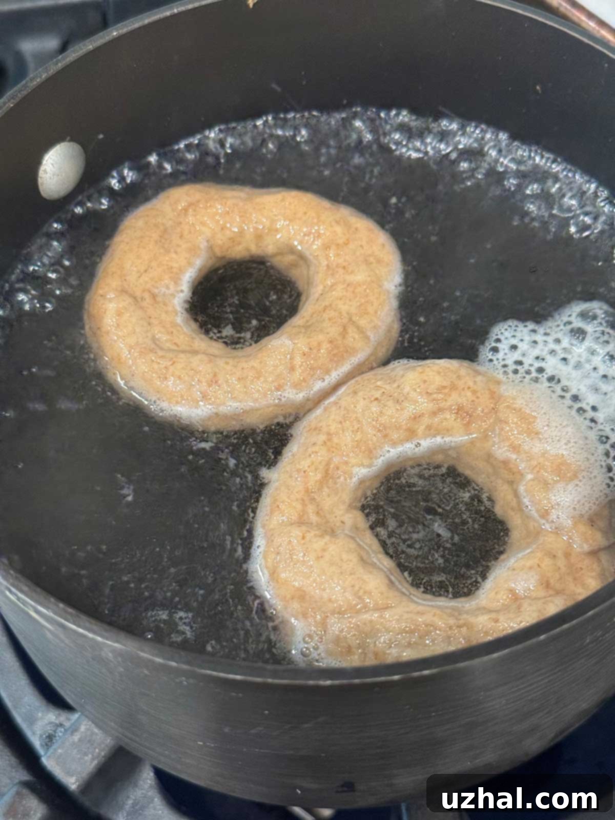 A pan of water with unbaked bagel dough boiling.